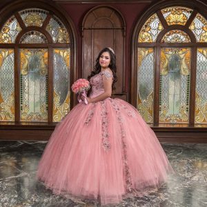 Fotografía de sesión de XV Años de una joven quinceañera, luciendo un vestido elegante. Posando con una sonrisa radiante. Fotografía por Click Fotografía.