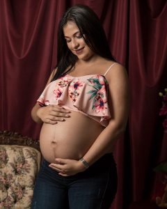 Captura de un momento especial: fotografía de sesión de embarazo irradiando amor y esperanza. La futura madre sonríe y acaricia su vientre. Fotografía por Click Fotografía.