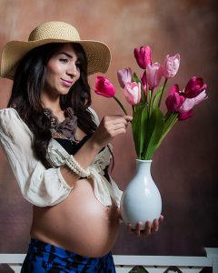 Retrato de una mujer embarazada en su sesión de fotos de maternidad. Viste ropa cómoda y elegante, resaltando su figura. Fondo neutro de estudio. Fotografía profesional por Click Fotografía.